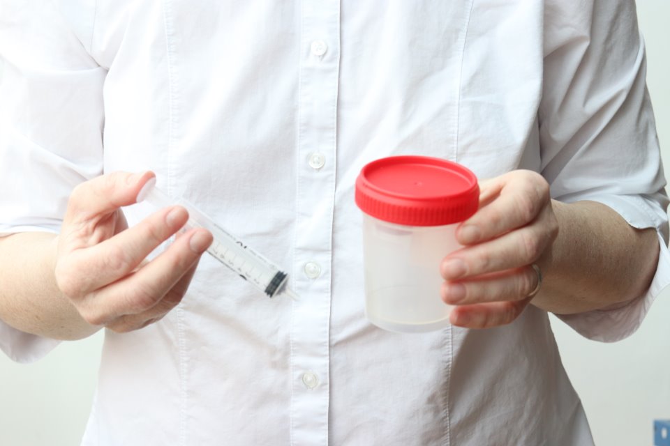 Woman holding a home insemination kit cup and syringe