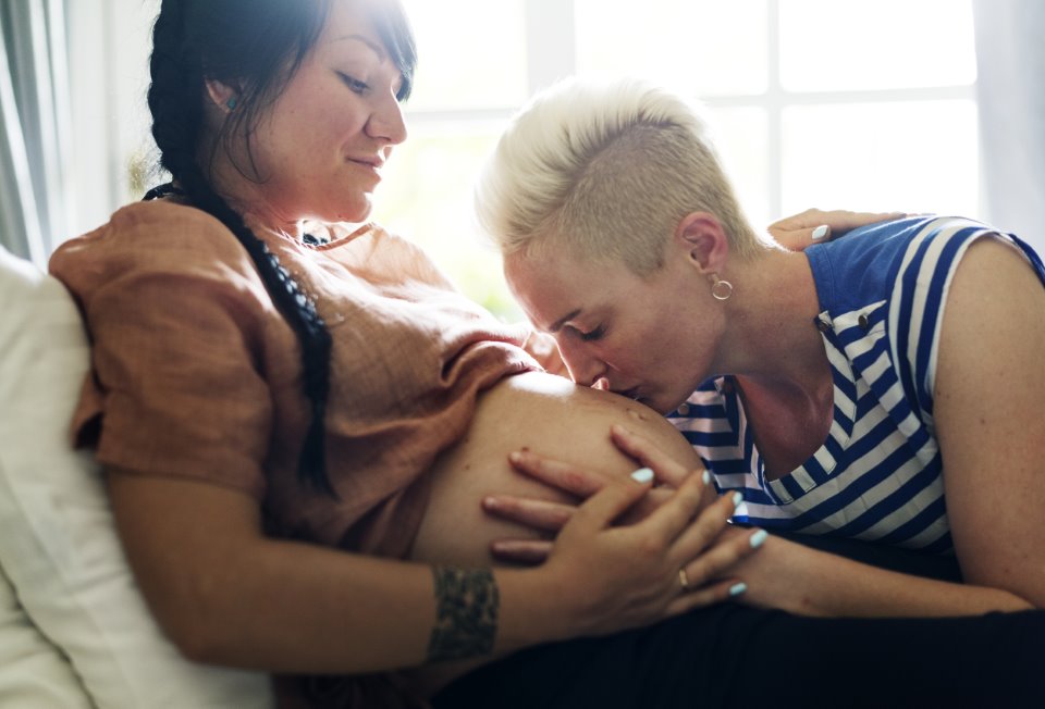 Lesbian parents kissing baby bump