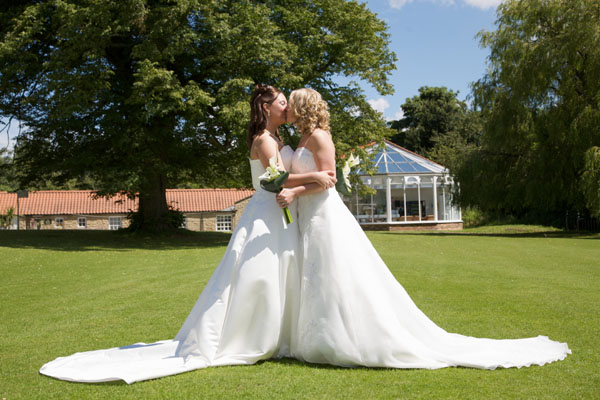 lesbian couple in wedding dresses getting married kissing